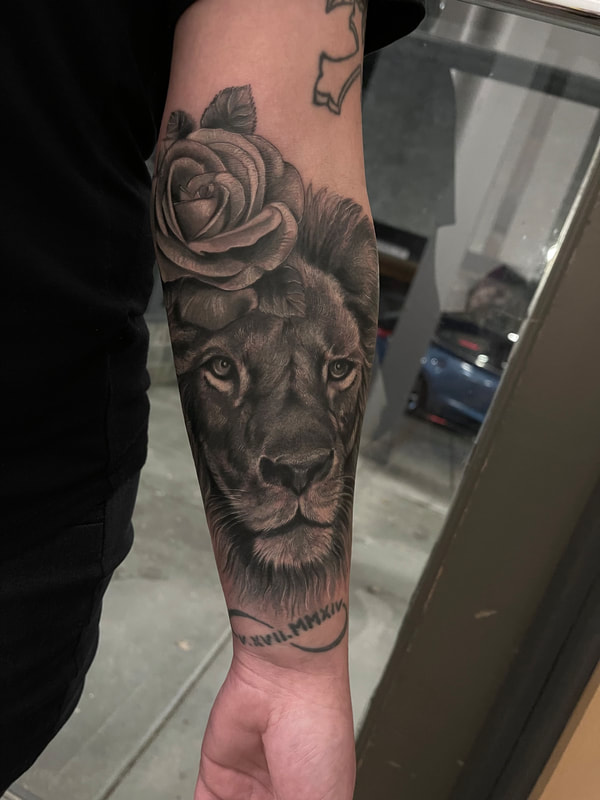 Realistic tattoo of a lion's face with a rose on a forearm.