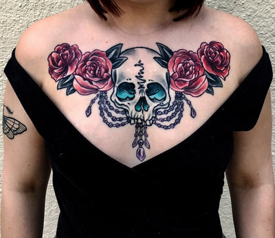 Neotraditional colored skull with roses and pearls on a woman's chest.