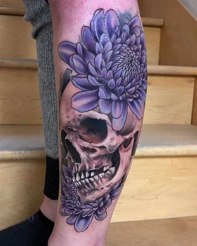 Realistic tattoo of a skull with purple peonies on a lower leg.